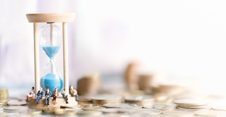 Miniature people: Elderly people sitting on hourglass with coins stack. social security income and pensions. Money saving and Investment. Time counting down for retirement concept. - obrazy, fototapety, plakaty