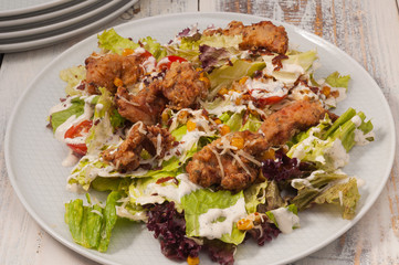 salad with deep-fried chicken, greens, corn and tomatoes