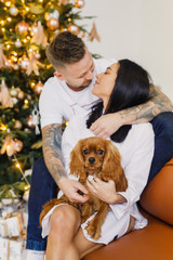 young beautiful couple in white clothes having fun with a small dog in their apartment