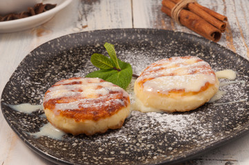 cheesecakes with condensed milk and a mint leaf on a dark plate