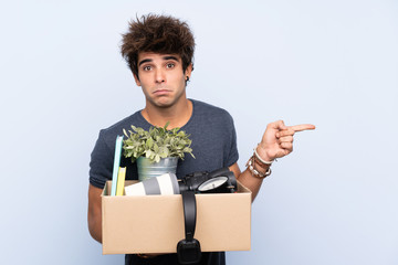 Man making a move while picking up a box full of things pointing to the laterals having doubts