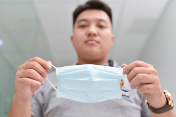 Asian man wearing respirator mask while walking in the office
