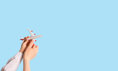 Toy airplane model in the hands of a child and an adult on a blue background. Copy space.