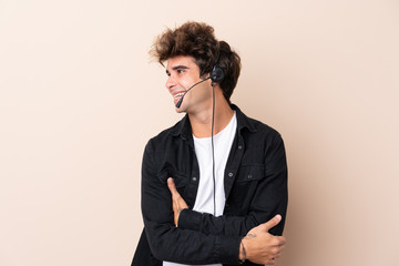 Telemarketer man working with a headset over isolated background looking to the side