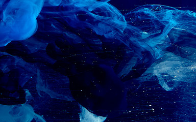 Blue watercolor ink in water on a black background. Colored space magic background. - obrazy, fototapety, plakaty