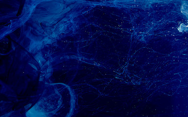 Abstract background. Blue watercolor ink in water on a black background.