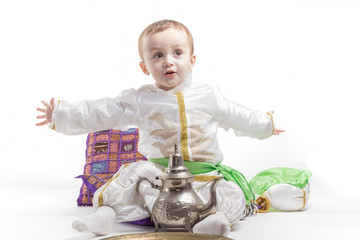 Caucasian little boy, dressed as Arab drinking tea, on white background.