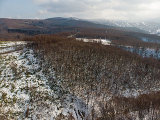 Fototapeta na wymiar Aerial view of a road during winter in the mountains of Tokiwa, Hokkaido where trees and snow can be clearly seen against a backdrop of mountains 