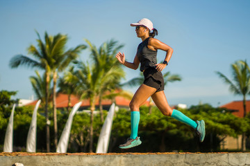 fitness lifestyle portrait of young attractive and athletic woman in compression running socks jogging happy on city park doing intervals workout in athlete training concept
