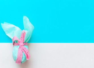 Egg gift in green paper packaging and with pink ribbon Easter Bunny wrap idea.  Minimal concept. Flat lay, Copy space, top view