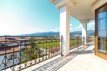 Large beautiful rich spacious veranda in the cottage with views of the mountains and the sea. Veranda with beautiful white tiles. Columns.  Wrought iron grilles, Italian style