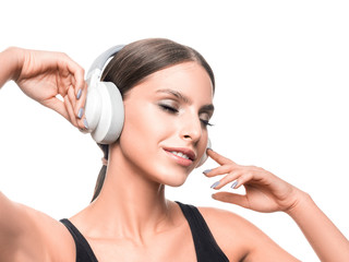 Smiling woman with closed eyes listening to the music via headphones.