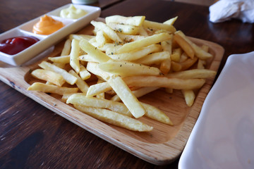 Tasty french fries on cutting board, on wooden table background.