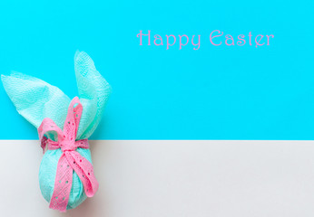 Egg gift in green paper packaging and with pink ribbon Easter Bunny wrap idea. Minimal concept. Flat lay, Copy space, top view