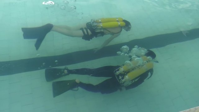 Two divers are trained in the pool. Learning to Scuba Dive in a Swimming Pool.  Discovery scuba diving course in deep pool