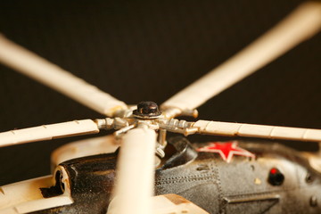 Miniature plastic model of helicopter among dark background scene. 