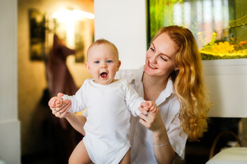 Happy baby boy having fun with mother on her hands