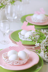 Happy easter. Decor and table setting of the Easter table is a vase with pink tulips and dishes of pink and green color.