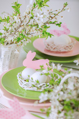 Happy easter. Decor and table setting of the Easter table is a vase with pink tulips and dishes of pink and green color.