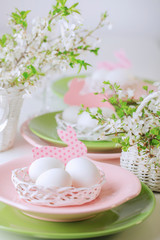 Fototapeta na wymiar Happy easter. Decor and table setting of the Easter table is a vase with pink tulips and dishes of pink and green color.