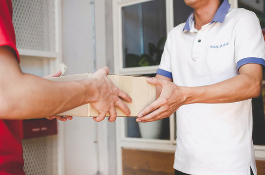 delivery service man in red uniform with young man customer receiving parcel post package box from courier at home, cargo shipping, express delivery service, online shopping and logistic concept