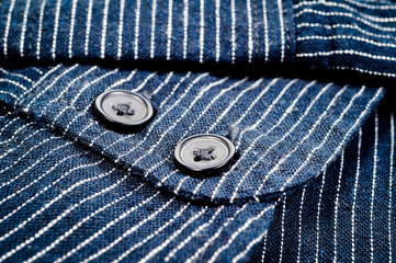 The texture of a denim shirt in dark blue with a small strip on the buttons. Background for fabric and clothes. Fashion, style and practicality.