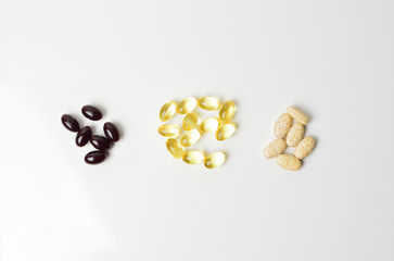 Three bunches of multivitamins, fish oil and astaxanthin. Omega-3 in the middle. White background. Close-up. Top view.