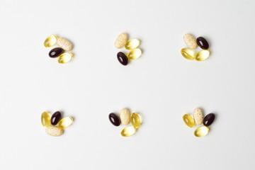 Day dosage of multivitamins, omega 3 and astaxanthin pills. Six bunches on a white background.
