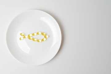 Fototapeta na wymiar Omega-3 fatty acids. Fish oil softgels on a white plate in a shape of a fish. Meal replacement. Nutrition prescription.