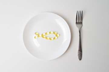 Fototapeta na wymiar Fish oil softgels on a white plate in a shape of a fish. Meal replacement. Nutrition prescription.