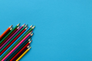 Fototapeta premium Group of multi-colored wooden sharpened pencils on a blue paper background with place for text.