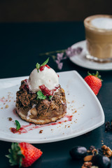brownie and ice cream on a white plate with coffee and fruits
