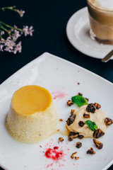 flan dessert on a white plate with nuts, fruits and coffee 