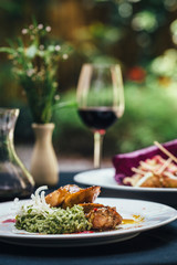 Table with wine, chicken with risotto and falafel on whiten white plates 