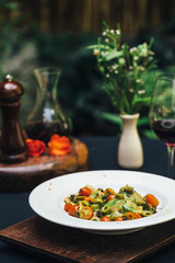 Pasta on a white plate with wine and flowers