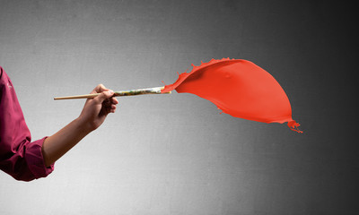 Close up artist hand painting red brush stroke