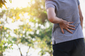 Closeup hands of woman touching her back pain in healthy concept on nature background.