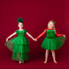 Beautiful little girl princesses dancing in luxury green dress isolated on red background. Carnival party with costumes