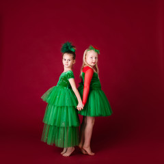 Beautiful little girl princesses dancing in luxury green dress isolated on red background. Carnival party with costumes