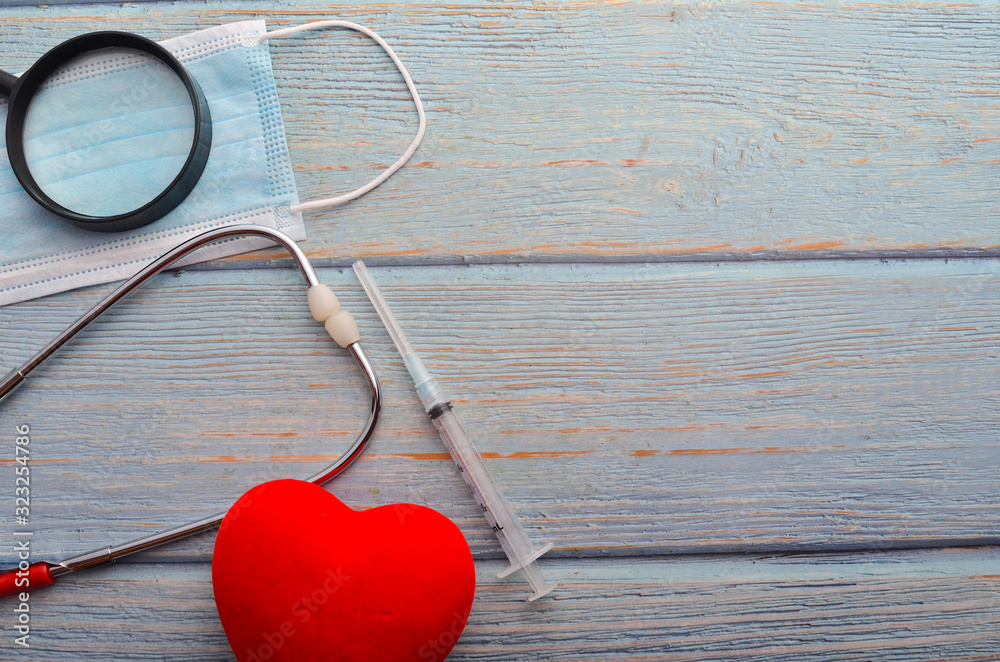 Wall mural red heart, face mask, stethoscope and syringe on wooden background. health concept.