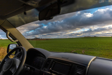 view from the car through the windshield on a green field in the sun