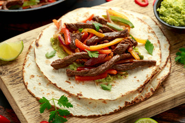 Beef Steak Fajitas with tortilla mix pepper, onion and avocado on wooden board