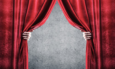 Concrete wall behind drapery curtain and hand opening it