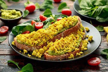 Scrambled Tofu crispy Toast with guacamole and spinach, tomato salad. Vegan vegetarian, plant based food