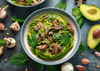 Vegan garlic mushroom pasta with spinach and avocado pesto drizzled with sesame seeds and roasted pine nuts