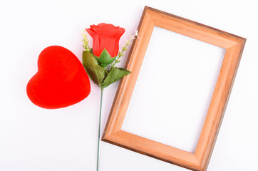 Flat lay view of artificial red roses with heart shape and wooden frame on white background. Love and Valentine's Day concept.