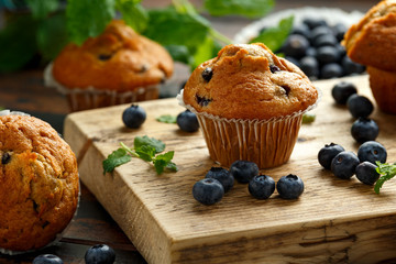 Blueberries muffins, cupcake with mint and berry on wooden board.