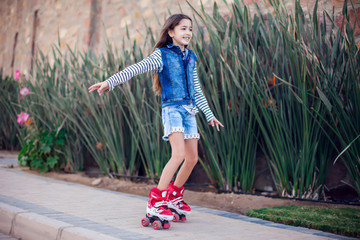 Smiling kid girl roller skate in the park. Children and activity concept