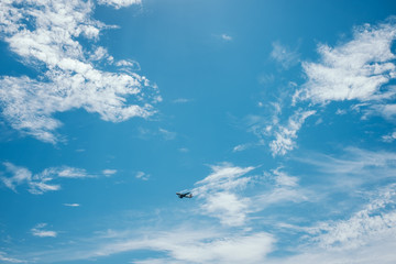 Flying airplane in the blue cloudy sky