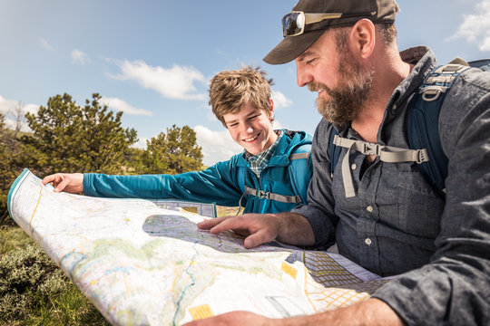 Father and son looking at map while hiking in rural prairie landscape. Cody, Wyoming, USA